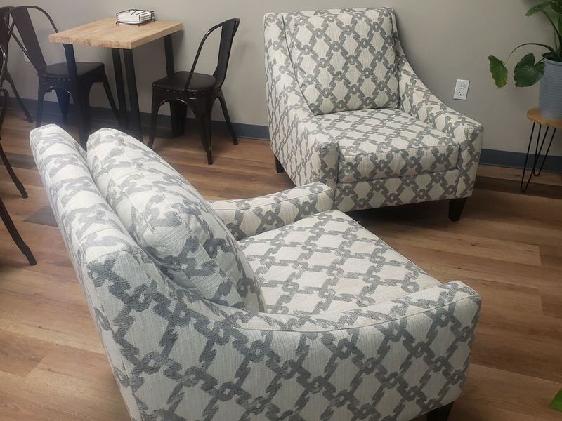 Two patterned armchairs and a small wooden table on the pale wood floor of the seating area.